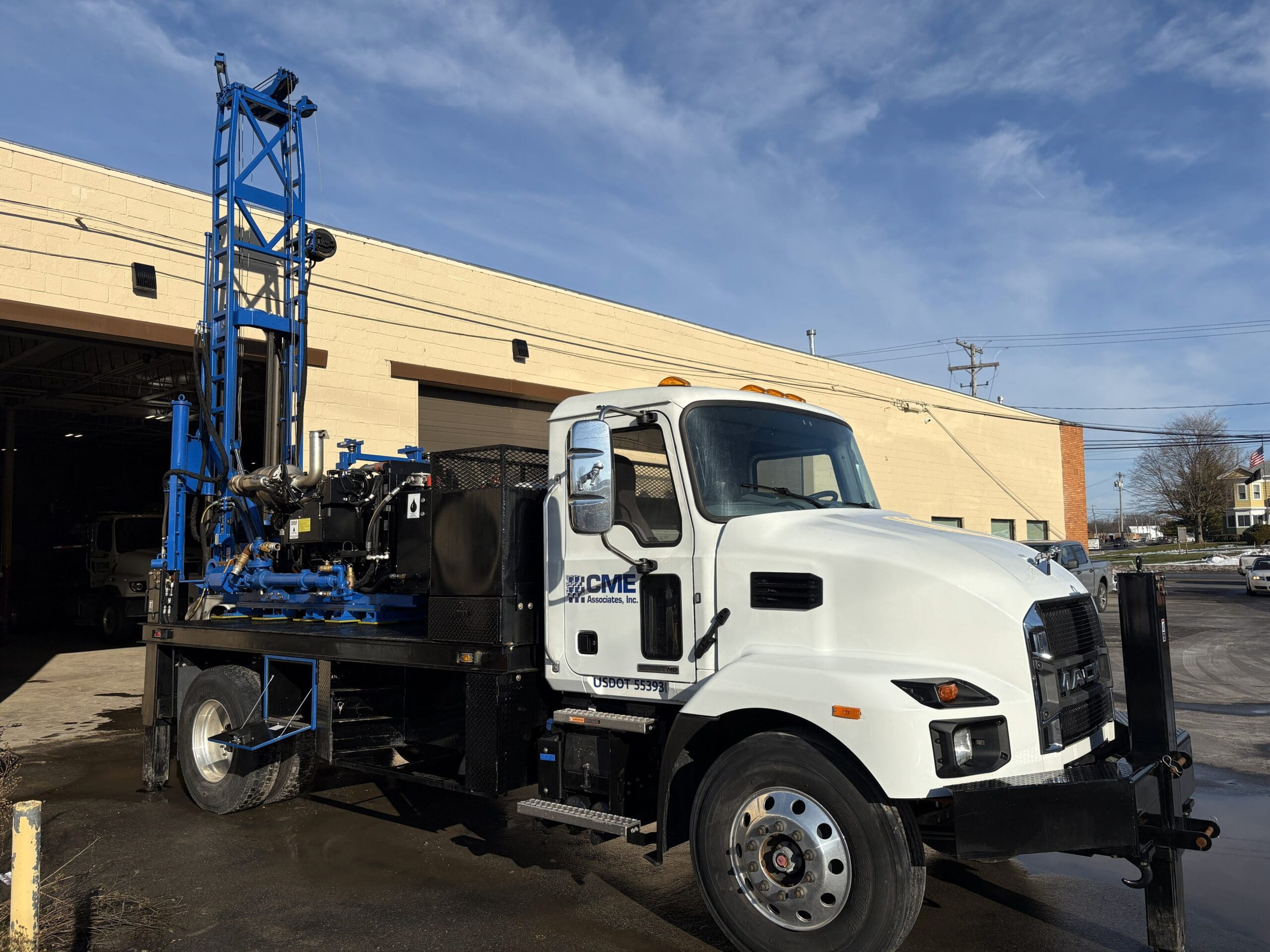 Truck-mounted D50 geotechnical drill rig by Diedrich Drill parked outside shop, featuring compact drilling equipment for soil sampling and SPT drilling.